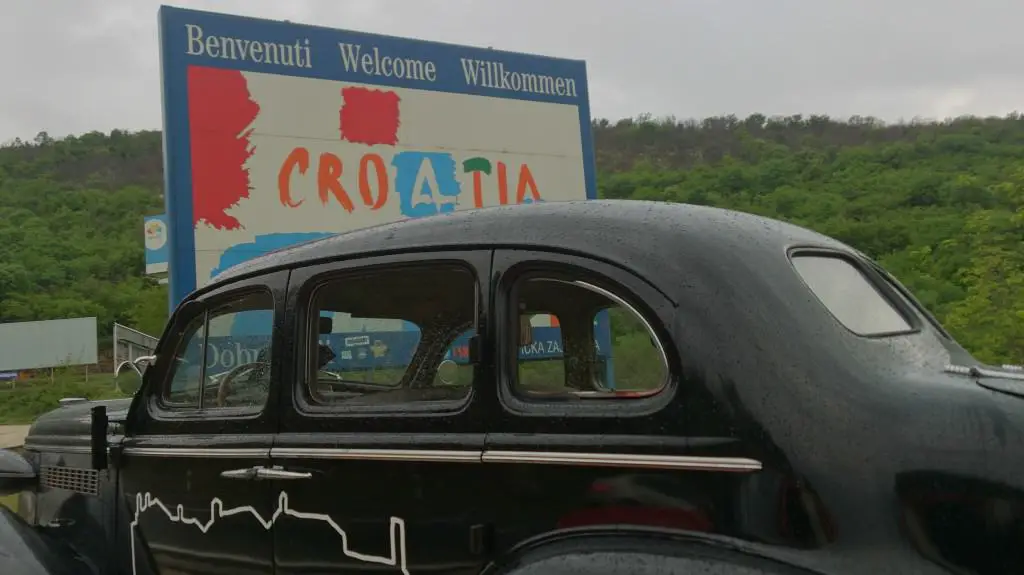 Willkommen in Kroatien Tafel mit schwarzem Oldtimer im Vordergrund in der Nähe von Umag