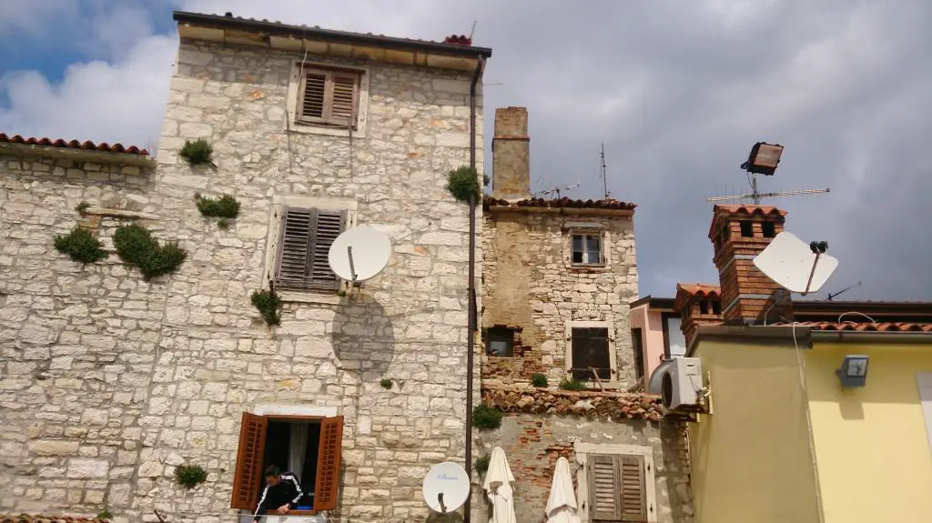 view of the old town of umag with houses made of stone, chimneys and clouds