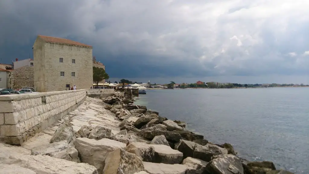 seafront in Umag with a view of the Adriatic Sea, stones, an old building and clouds
