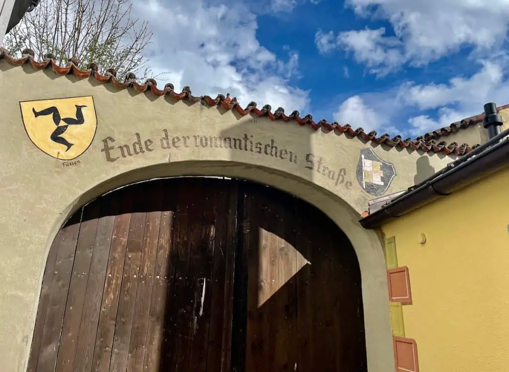 Füssen Altstadt Tor mit Ende der romantischen Straße Schrift neben Füssen Wappen