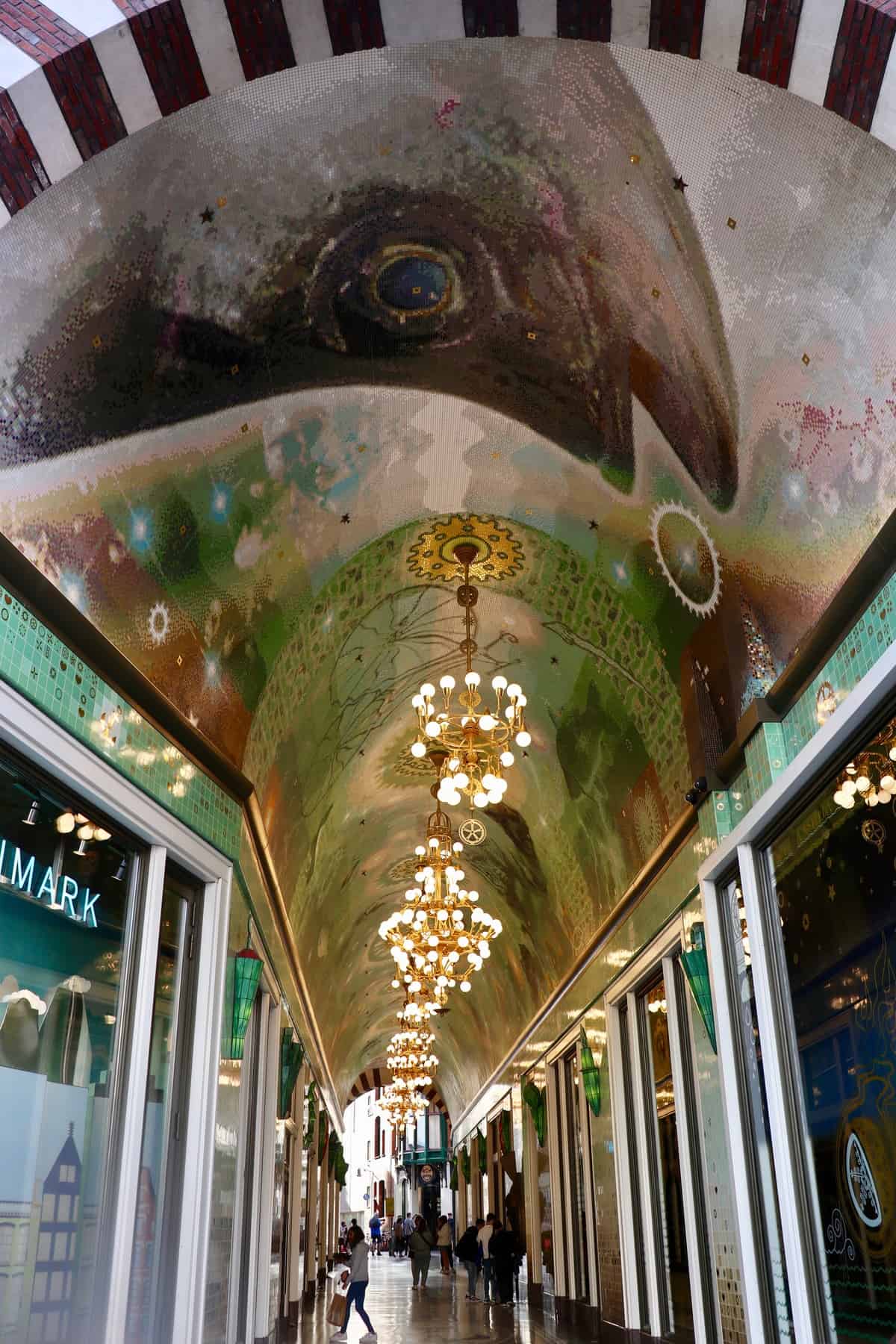 Beurspassage in Amsterdam mit wunderschönen Mosaiken an der Decke in Form von Fischen und Kristalllustern an der Decke.