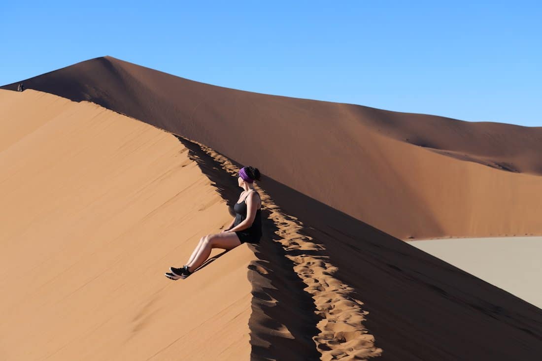 Reisebloggerin Christina sitzt auf der Düne mit Blick auf Big Daddy und Deadvlei in der Namibwüste