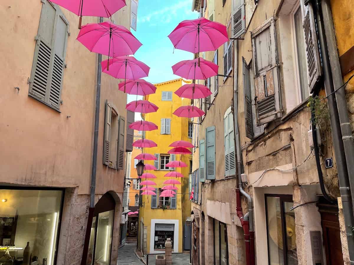 pinke Schirme hängen zwischen den engen Häuserfronten in der Altstadt von Grasse