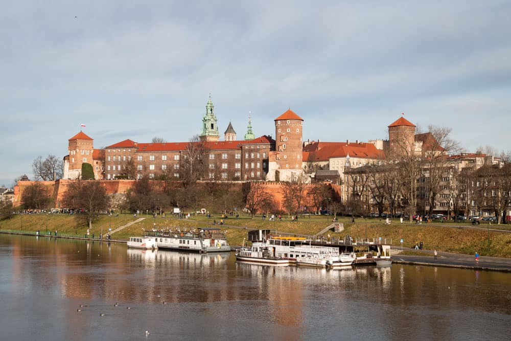 Burg Wawel in Krakau mit Fluss und Booten im Vordergrund