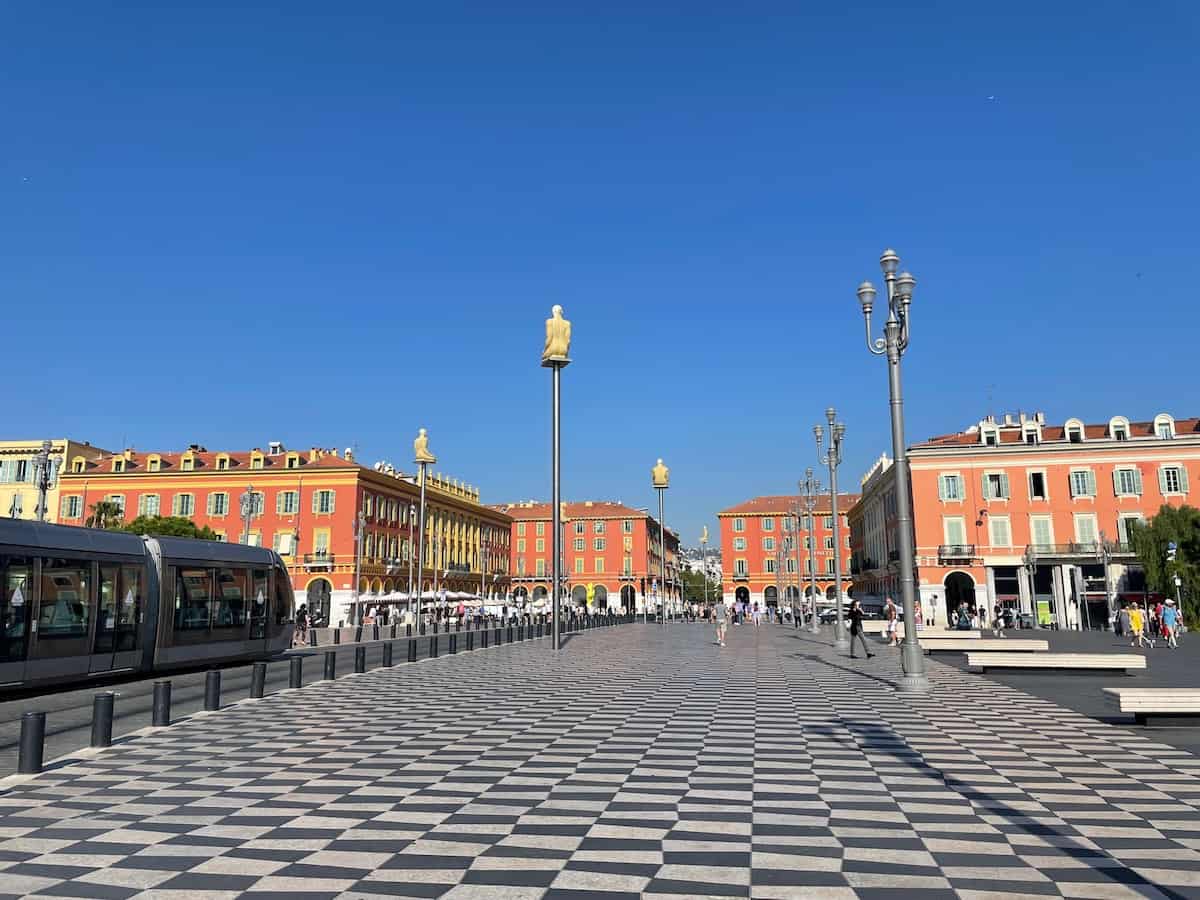 Blick auf die in Schachmuster gepflasterte Straße vor dem Place Masséna