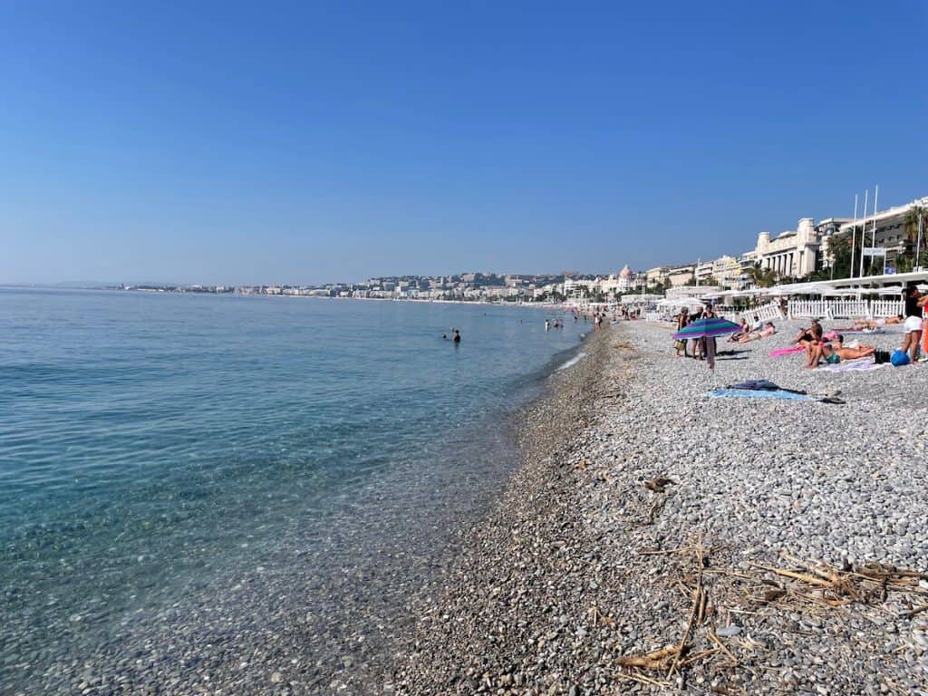 kristallklares Wasser und Kieselstrand mit Blick auf Promenade des Anglais in Nizza
