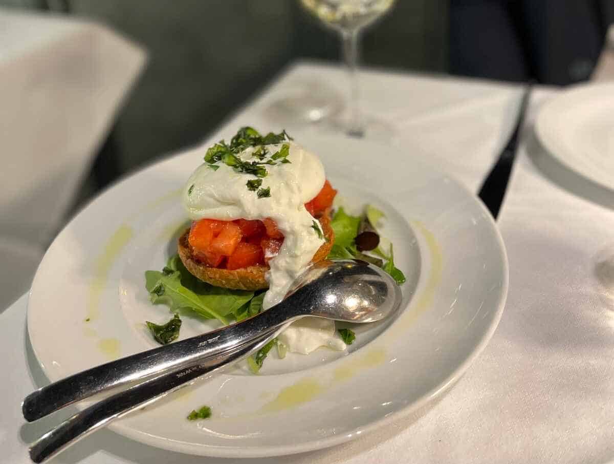 Das Mailänder Essen wie hier eine Vorspeise mit Bruschetta Burrata und mit Tomaten und Kräutern garniert gehört zu einem Besuch in Mailand unbedingt dazu.