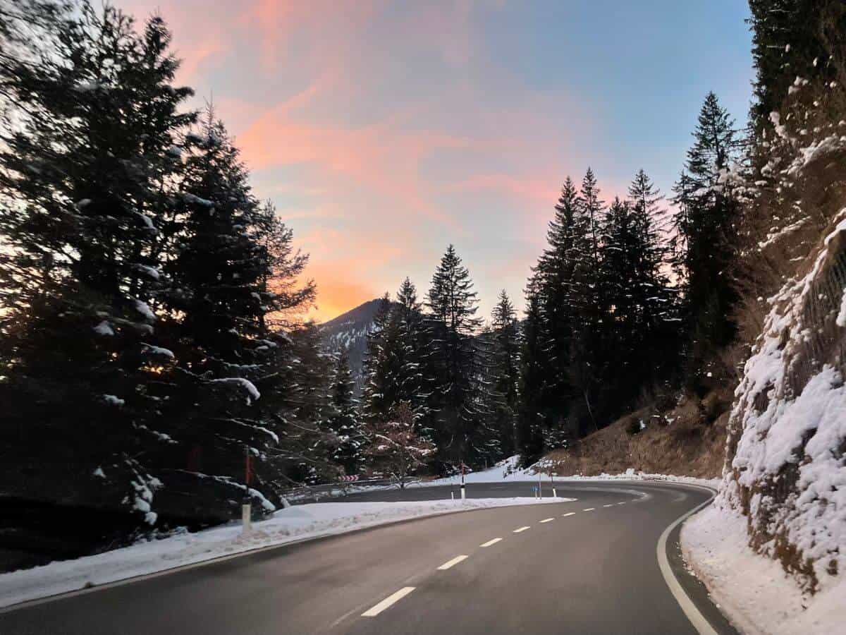 pass in Tyrol in winter with a winding road, snow and a sunset