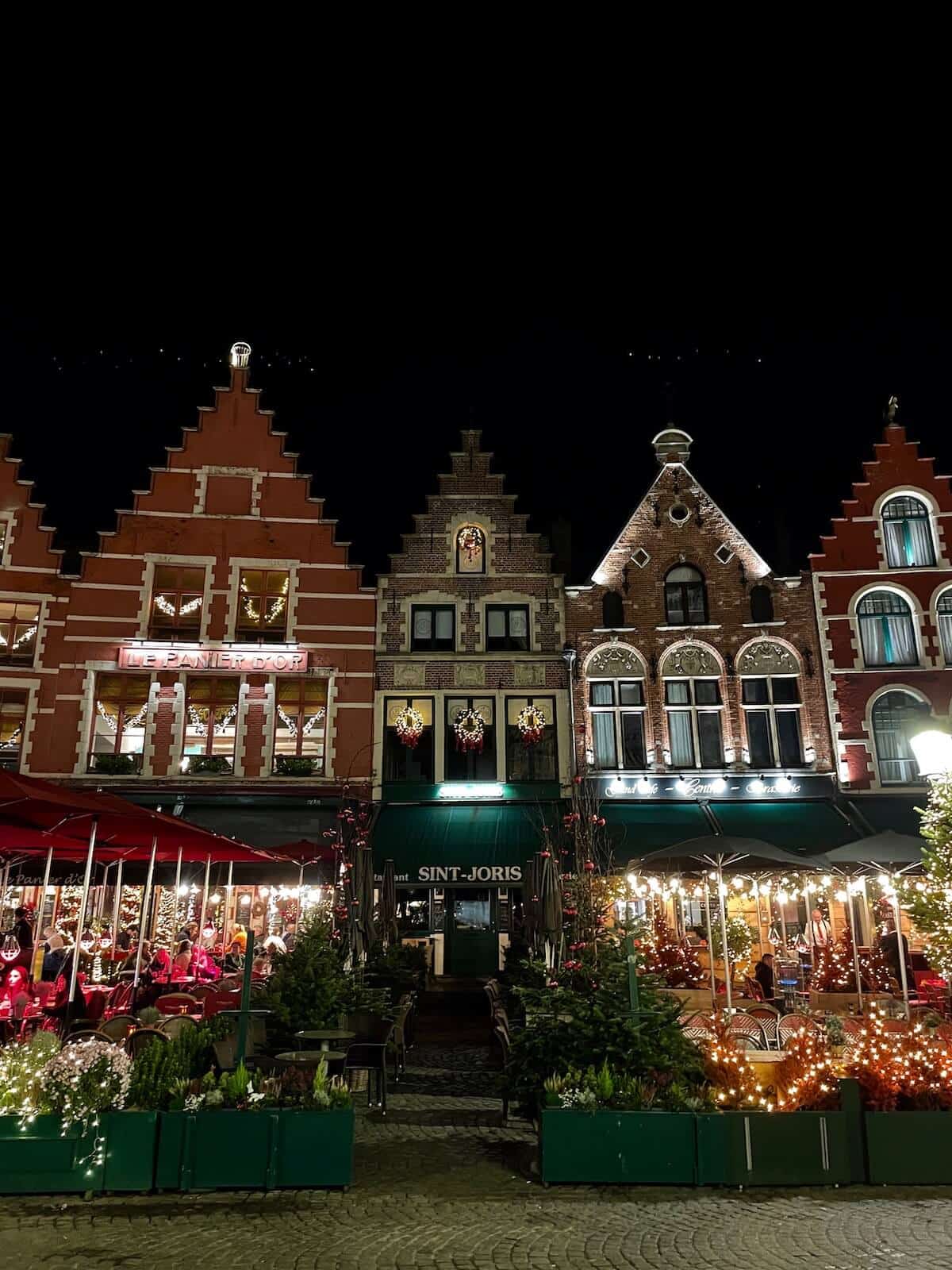 typical, colorful, narrow houses at the Grote Markt with Christmas decoration and a restaurant in the front.