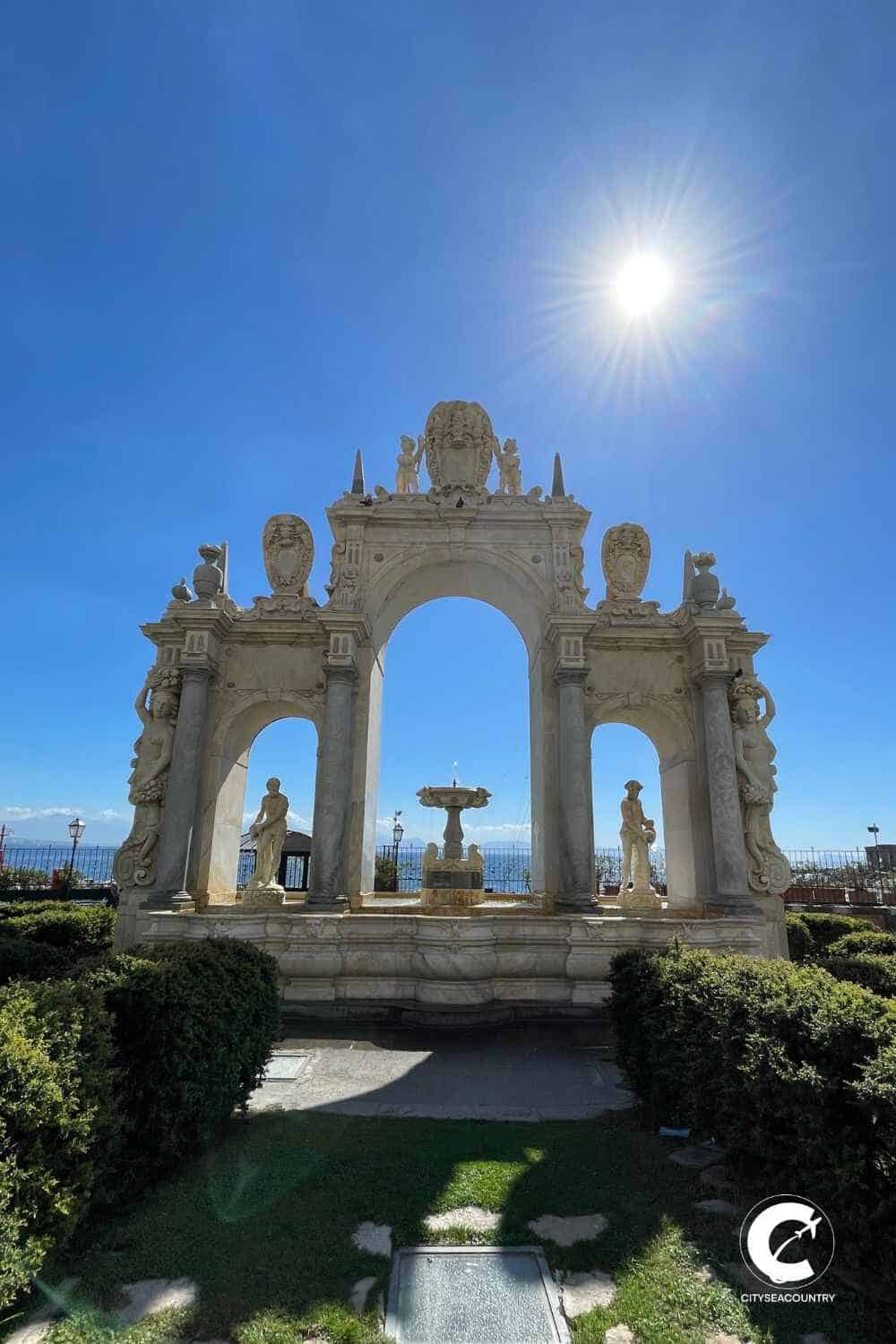 Blick auf den weißen Brunnen Fontana di Gigante in Form von drei Bögen mit einem Springbrunnen in der Mitte und weißen Marmorfiguren.