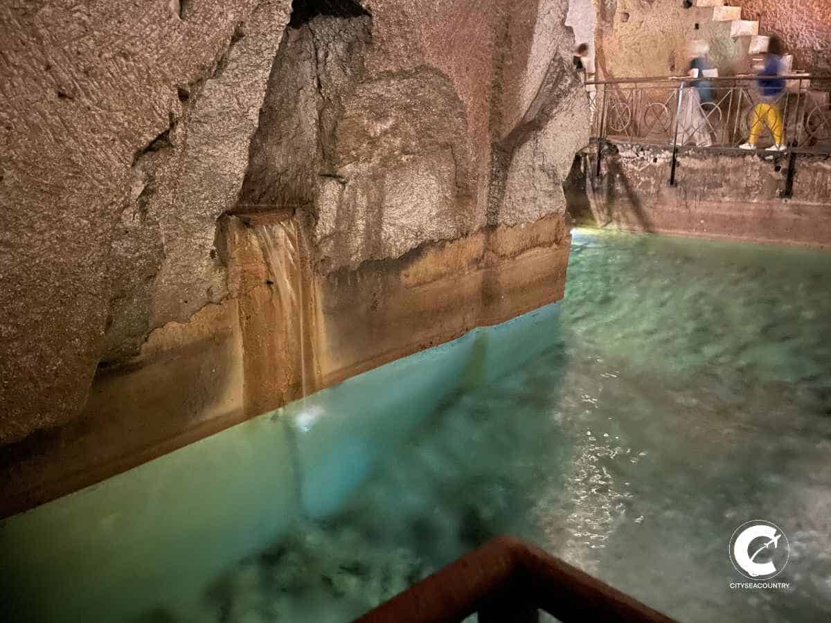 Unterirdisches Neapel mit einem kristallklaren grünlichen mit Wasser gefüllten Basin und bräunlichen Wänden.