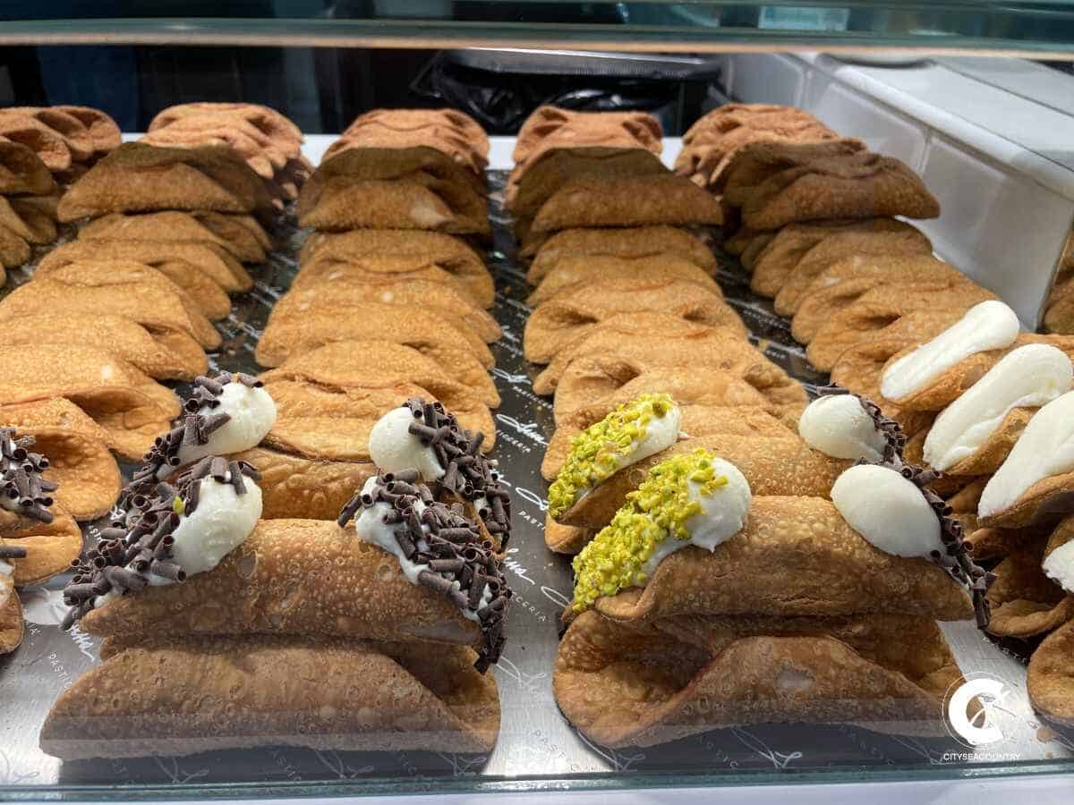 Runde, gefüllte Dessertrollen in einer Glasvitrine in der Markthalle Mercato Cenetrale in Florenz