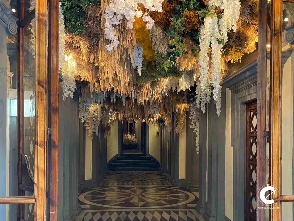 Eingang zur ältesten Apotheke der Welt mit einem blank polierten und mit Mosaik verzierten Boden, sowie einer Decke, welche mit Trockenblumen verziert ist.