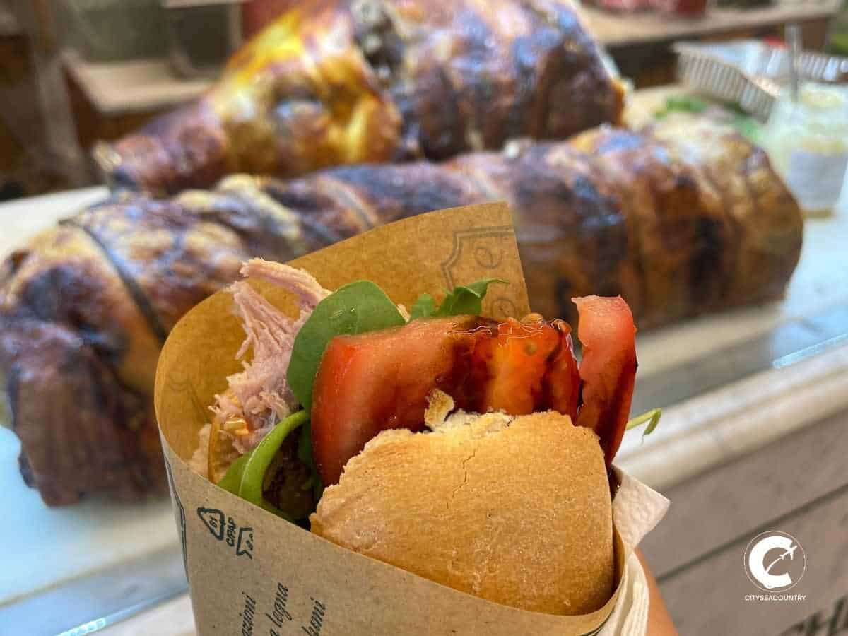 Typisches Street Food in Florenz: Sandwich in einer braunen Tüte mit Tomaten, frischem Salat und Schweinefleisch