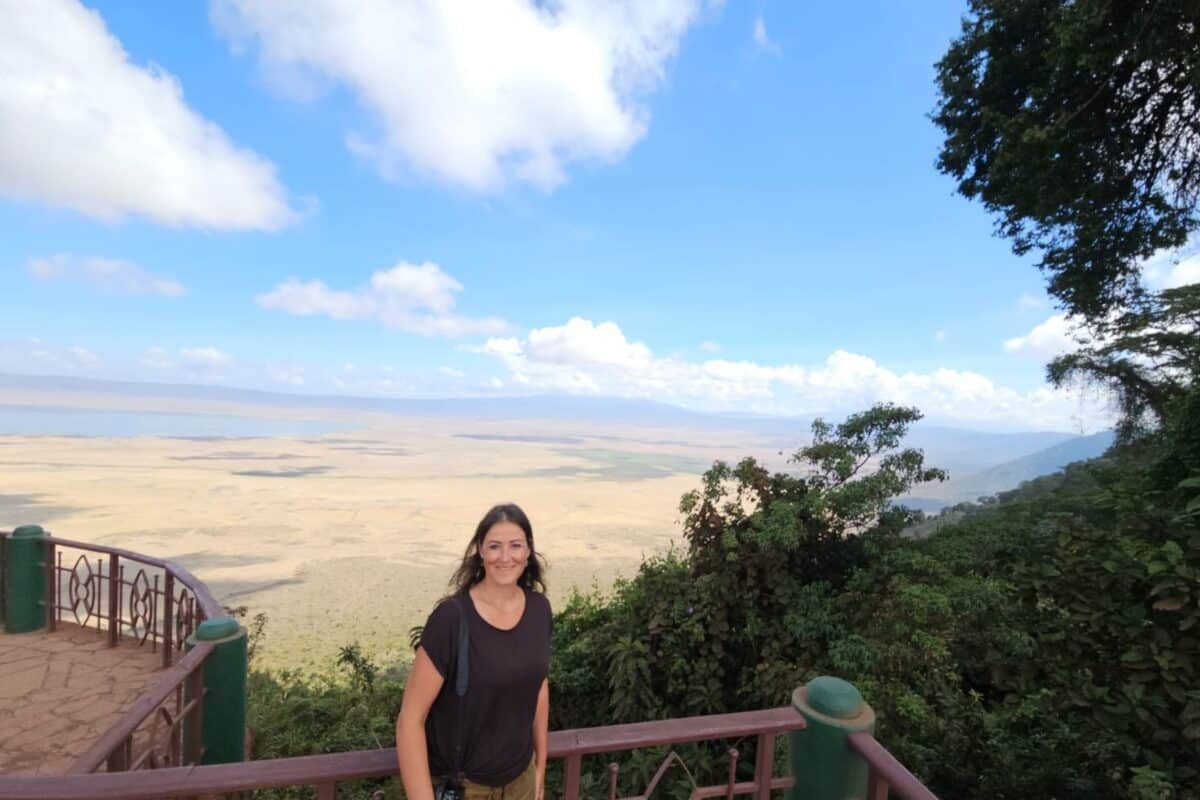 Author Christina standing at the Ngorongoro crater viewpoints with a view of the flat land below.