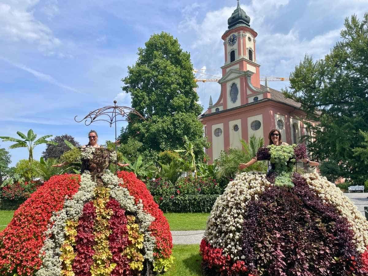 Kleider aus Blumen mit Kirche und Palmen im Hintergrund auf der Blumeninsel Mainau am Bodensee