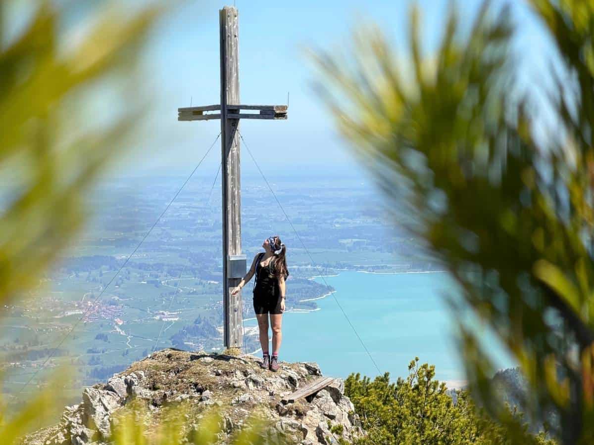 Wanderin am Gipfelkreuz bei einer grenznahen Wanderung in Tirol und dem Allgäu