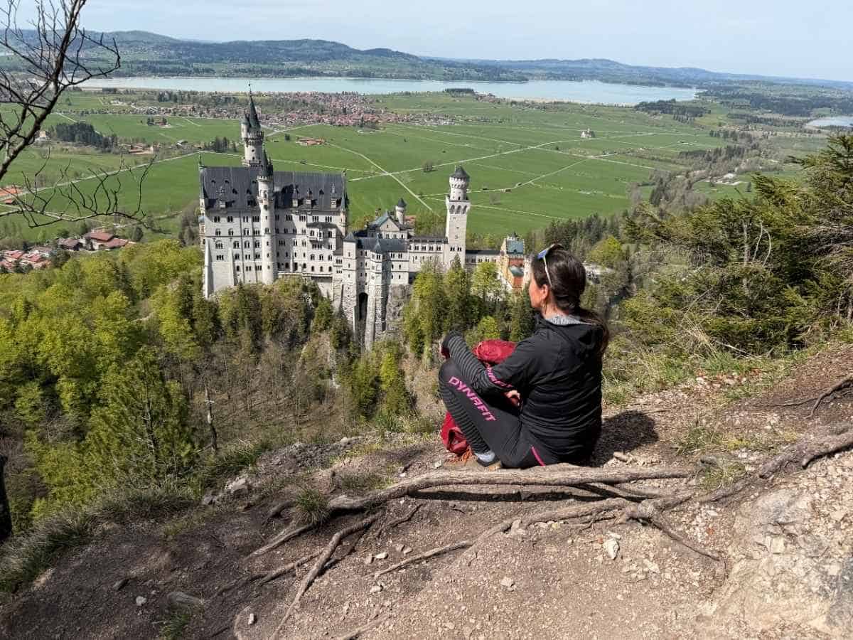 Wanderin beim Aussichtspunkt mit Schloss Neuschwanstein im Frühling