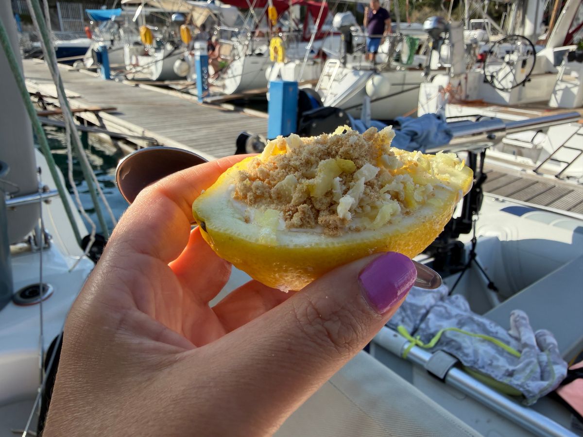Hand mit Zitronenschale und süßer Füllung vor dem Anlegesteg in der Marina in Milna Kroatien