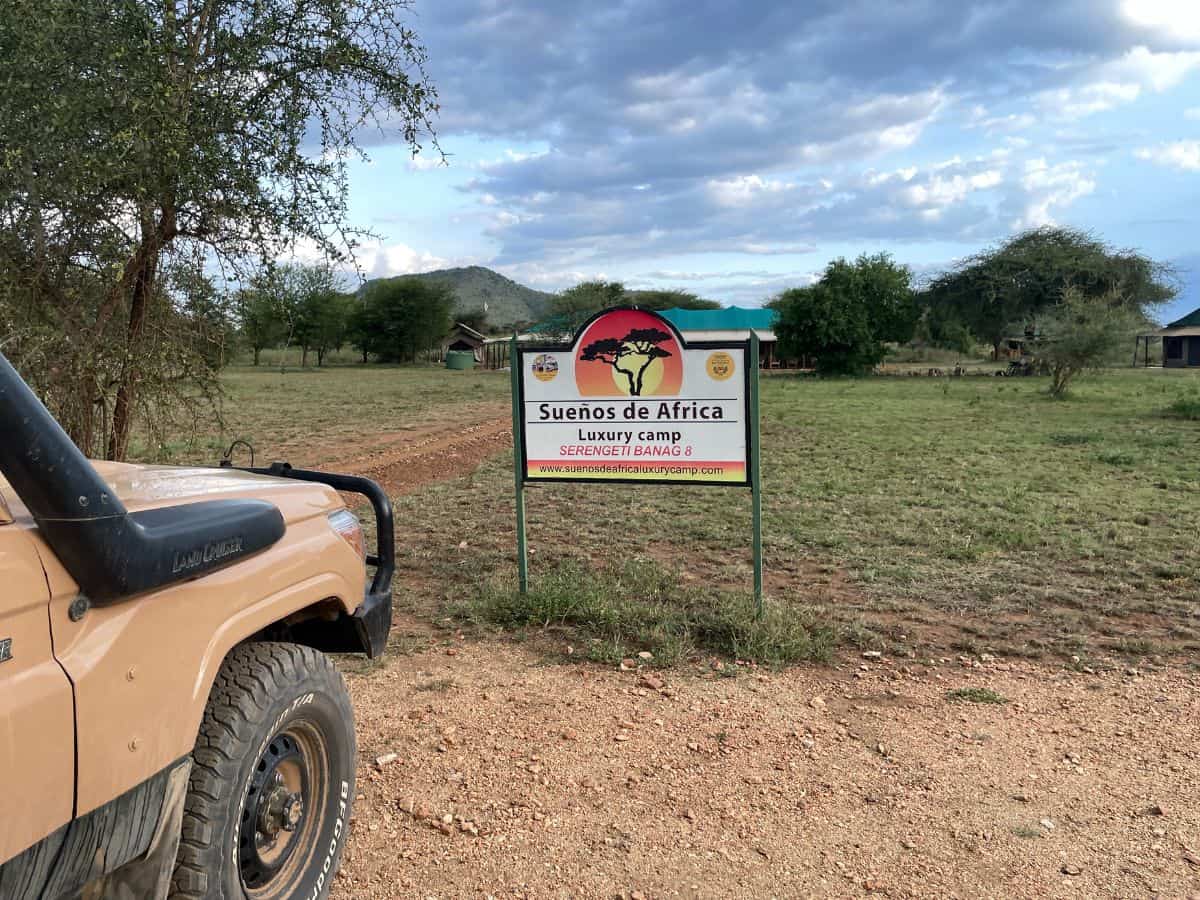 Blick auf den Jeep und das Schild für das Tented Camp inmitten der Serengeti